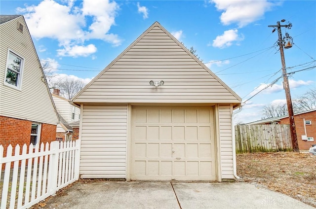 detached garage featuring driveway and fence