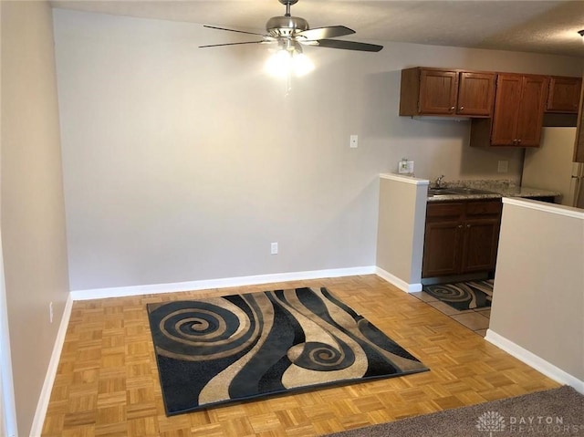 kitchen featuring a ceiling fan, brown cabinets, and baseboards