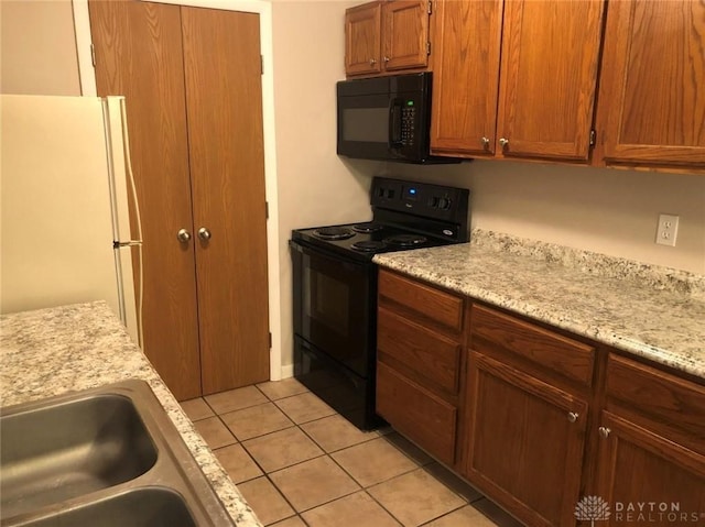 kitchen featuring brown cabinets, light tile patterned flooring, a sink, and black appliances