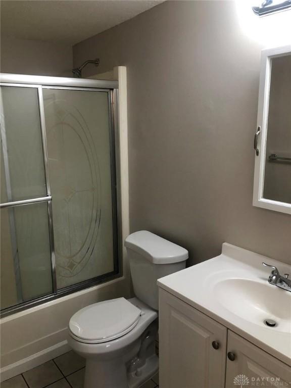 bathroom featuring toilet, shower / bath combination with glass door, vanity, and tile patterned floors