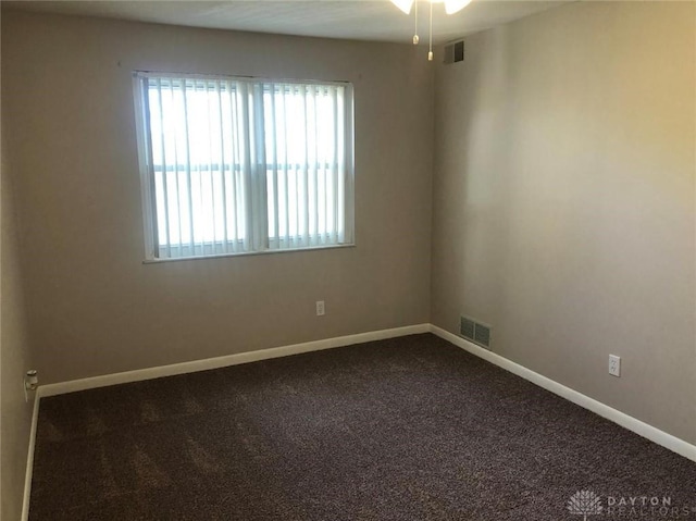 unfurnished room featuring baseboards, visible vents, and dark colored carpet