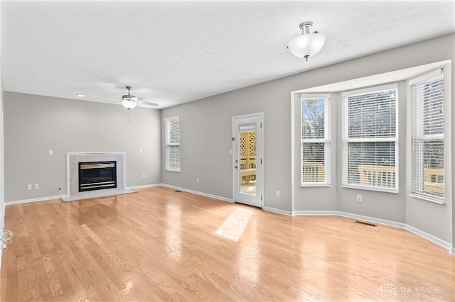 unfurnished living room featuring light wood-style floors, baseboards, and a tile fireplace