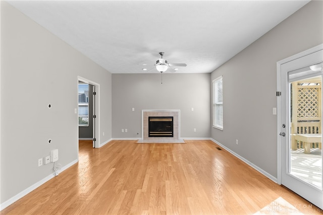 unfurnished living room featuring a fireplace, visible vents, light wood-style floors, a ceiling fan, and baseboards