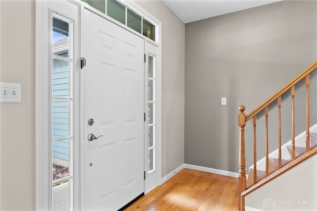 entrance foyer featuring a wealth of natural light, stairway, baseboards, and wood finished floors