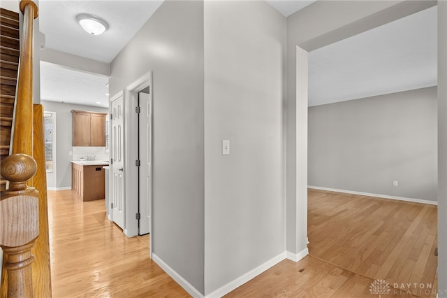 corridor with light wood-style flooring and baseboards