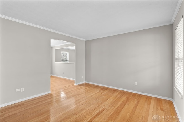 unfurnished room with baseboards, ornamental molding, and light wood-style floors