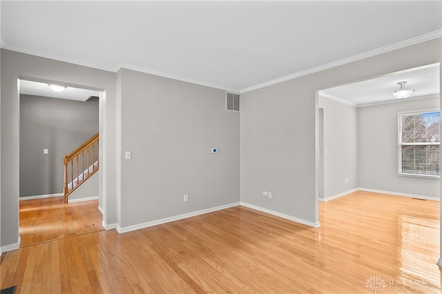 unfurnished room featuring light wood-style flooring, ornamental molding, stairway, and baseboards