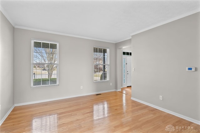 unfurnished room with ornamental molding, baseboards, and light wood finished floors