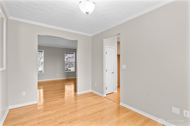 unfurnished room with light wood-type flooring, crown molding, and baseboards