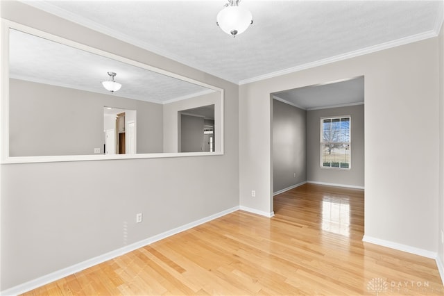 spare room featuring crown molding, a textured ceiling, baseboards, and wood finished floors