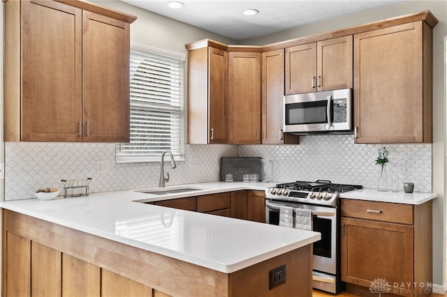 kitchen featuring appliances with stainless steel finishes, light countertops, a sink, and tasteful backsplash