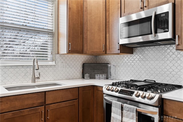 kitchen featuring appliances with stainless steel finishes, backsplash, a sink, and light countertops