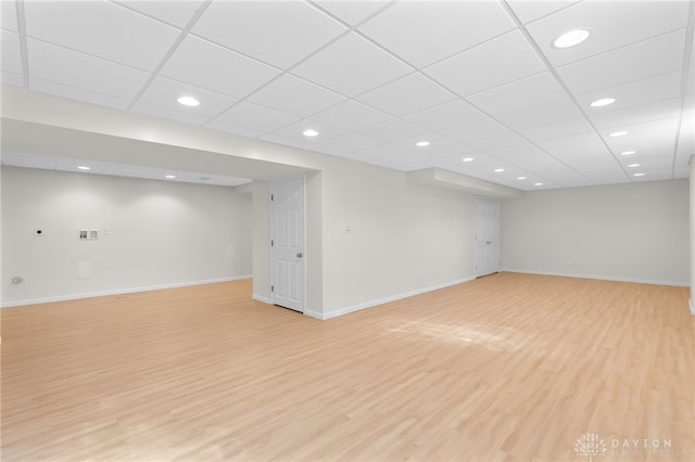 finished below grade area with a paneled ceiling, recessed lighting, light wood-style flooring, and baseboards