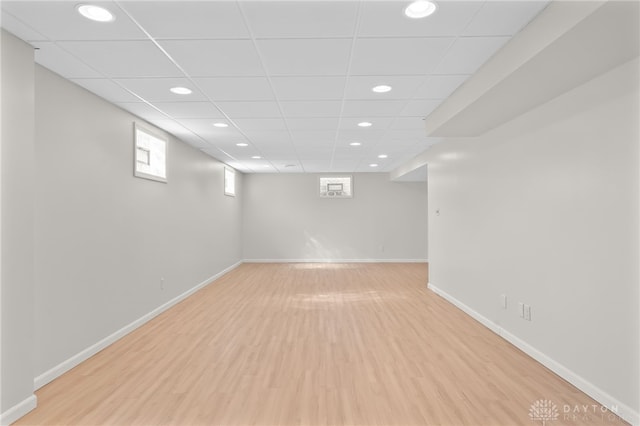 below grade area featuring light wood-type flooring, a drop ceiling, baseboards, and recessed lighting