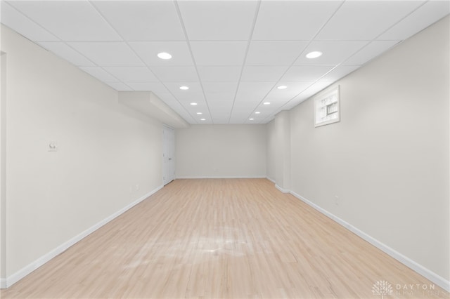 basement featuring light wood-type flooring, baseboards, a paneled ceiling, and recessed lighting