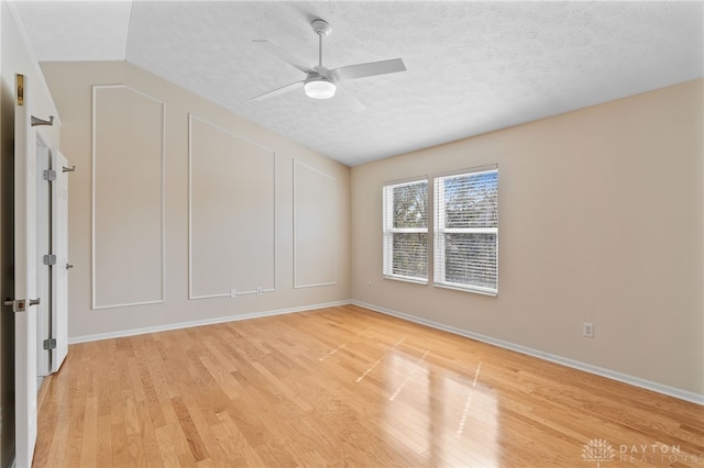 empty room with light wood-type flooring, vaulted ceiling, and a textured ceiling