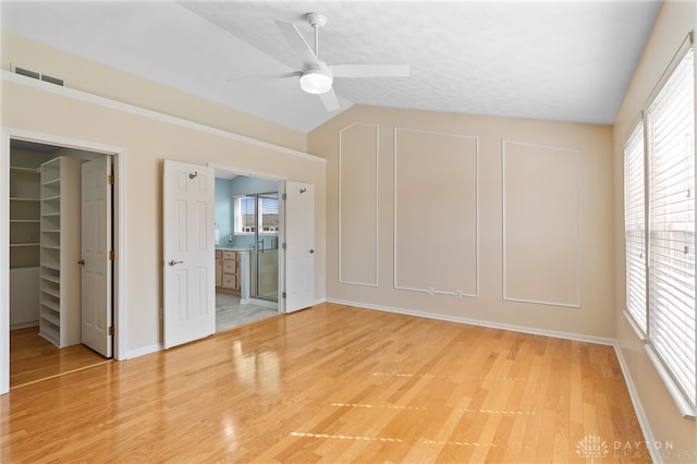 spare room featuring visible vents, light wood-style floors, vaulted ceiling, a textured ceiling, and ceiling fan