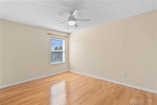 empty room featuring a textured ceiling, ceiling fan, light wood-type flooring, and baseboards