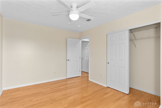 unfurnished bedroom featuring a textured ceiling, a closet, light wood-type flooring, and baseboards