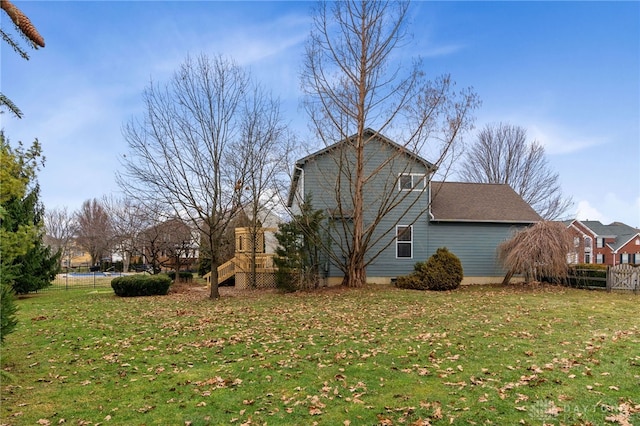 view of side of home featuring a lawn and fence