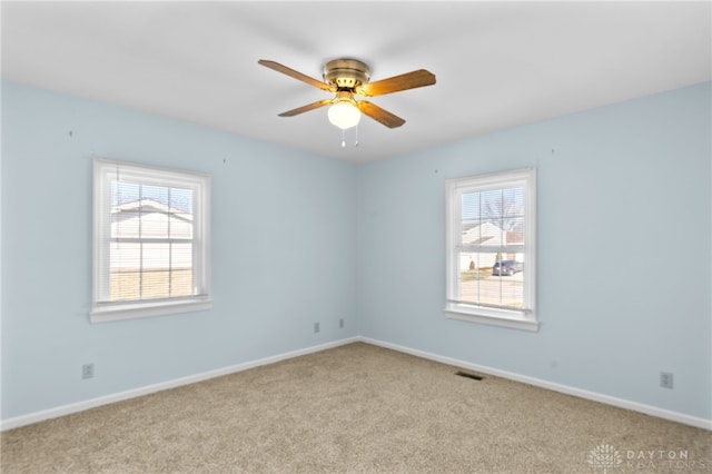 unfurnished room featuring carpet floors, a healthy amount of sunlight, ceiling fan, and baseboards