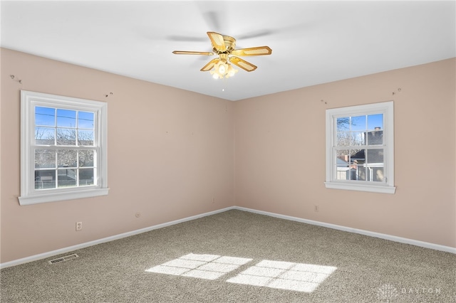 carpeted empty room featuring a ceiling fan, visible vents, and baseboards