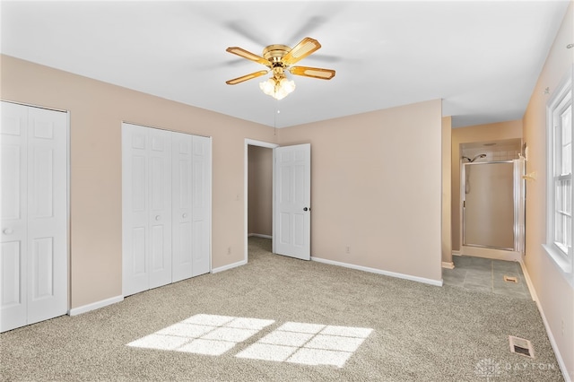 unfurnished bedroom with carpet floors, baseboards, visible vents, and multiple closets