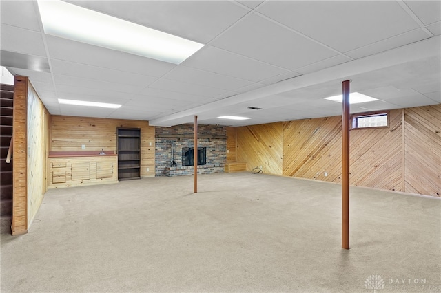 finished basement featuring carpet, a drop ceiling, and wooden walls