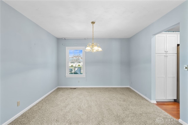 spare room featuring baseboards, carpet, and a notable chandelier