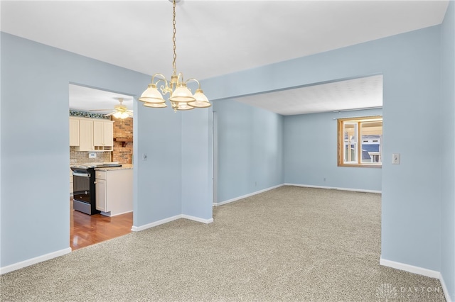 unfurnished dining area with carpet floors, baseboards, and ceiling fan with notable chandelier