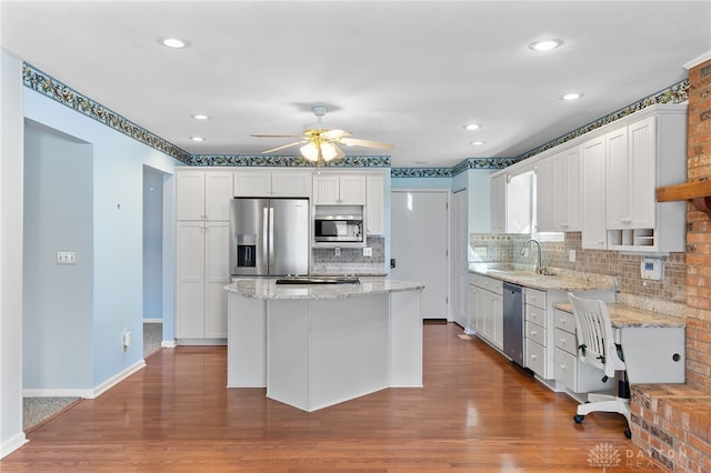 kitchen featuring stainless steel appliances, a sink, a center island, and white cabinets