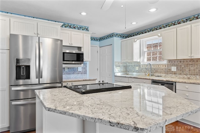 kitchen featuring light stone countertops, a kitchen island, appliances with stainless steel finishes, and backsplash