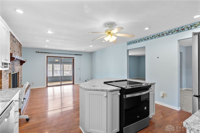 kitchen with white cabinets, dark wood-style floors, a fireplace, stainless steel dishwasher, and range with electric stovetop