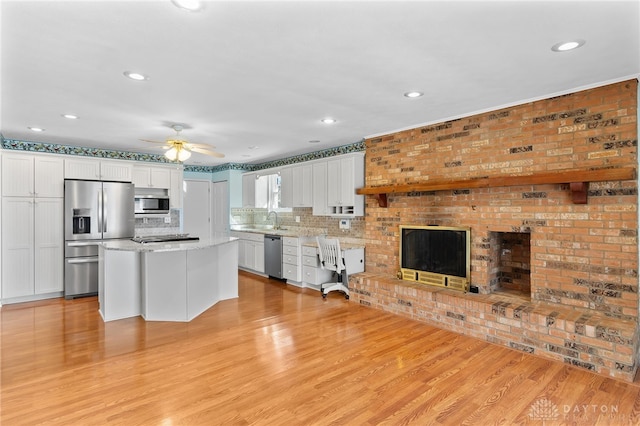 kitchen featuring stainless steel appliances, white cabinets, ceiling fan, and light wood finished floors