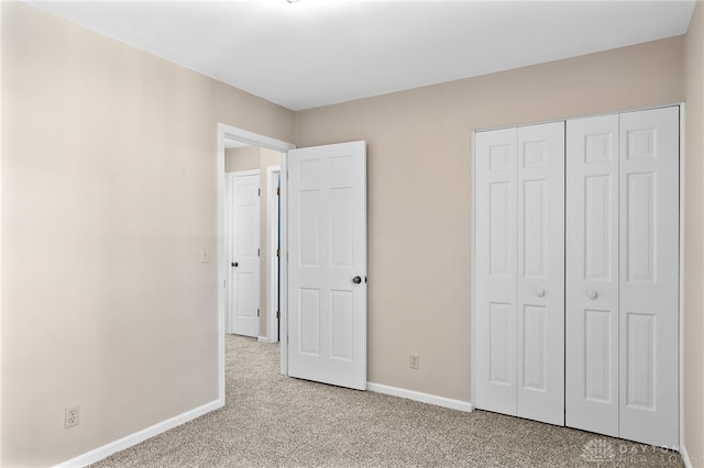 unfurnished bedroom featuring light carpet, baseboards, and a closet