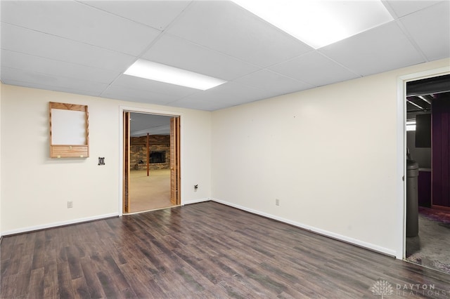 unfurnished room with dark wood-type flooring, a drop ceiling, and baseboards