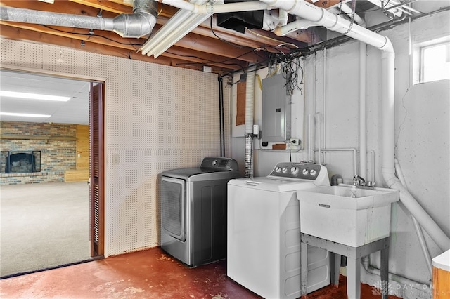 clothes washing area with washing machine and dryer, laundry area, a sink, a brick fireplace, and electric panel