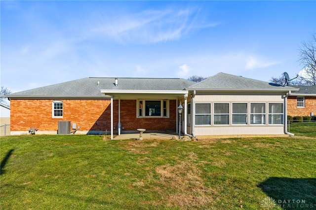 rear view of property with a yard, a sunroom, a patio, and brick siding