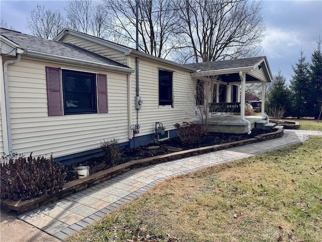 view of front of property with a porch, roof with shingles, and a front lawn