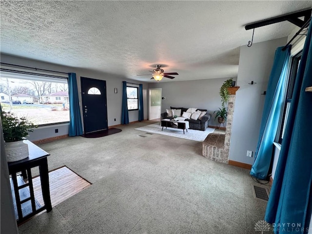 carpeted foyer with a textured ceiling, baseboards, a ceiling fan, and a healthy amount of sunlight