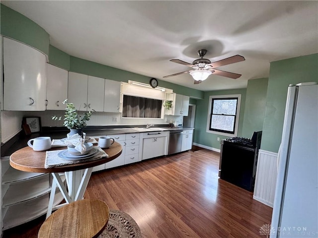 kitchen with dark wood-type flooring, white cabinets, stainless steel dishwasher, freestanding refrigerator, and gas stove