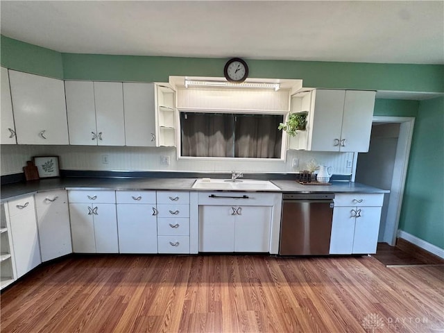 kitchen with dark countertops, a sink, stainless steel dishwasher, and open shelves