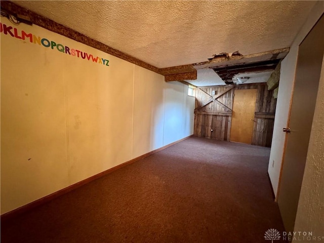 interior space with a textured ceiling, carpet flooring, and baseboards