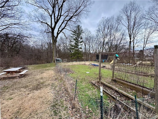 view of yard with a garden, fence, and a playground