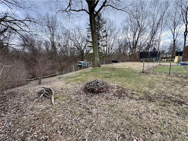 view of yard with a trampoline and a fire pit