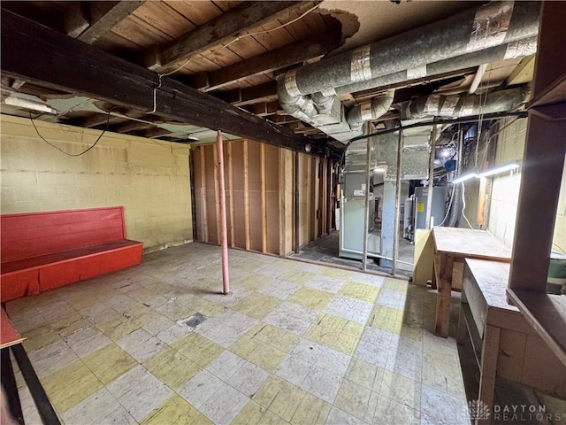 unfinished basement with concrete block wall, water heater, and heating unit