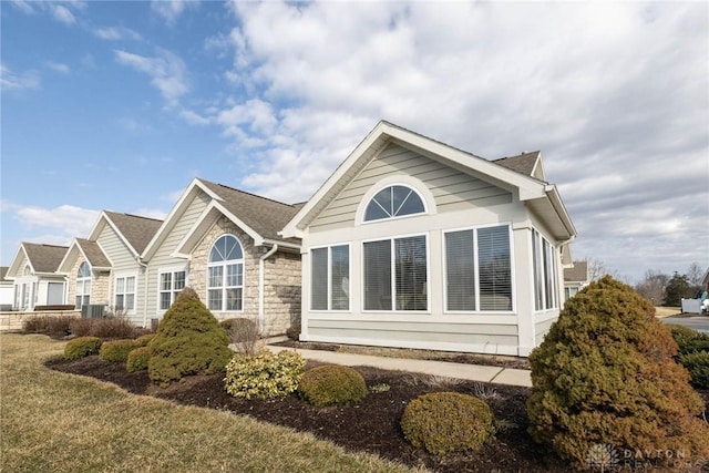 view of side of home featuring stone siding and a lawn