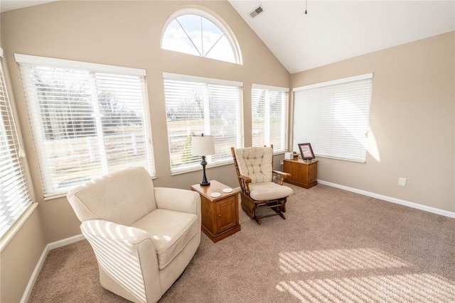 sitting room with baseboards, high vaulted ceiling, visible vents, and light colored carpet