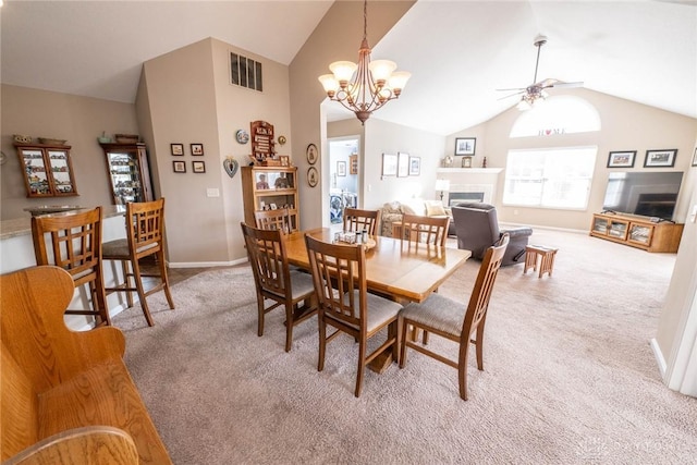 dining space with high vaulted ceiling, light colored carpet, ceiling fan with notable chandelier, a fireplace, and visible vents