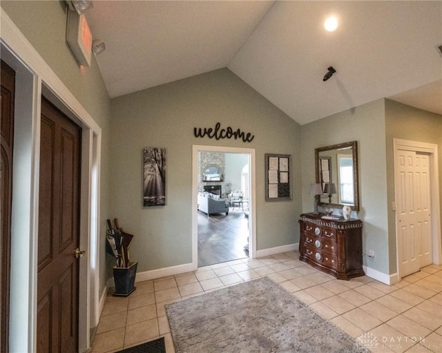 entrance foyer with light tile patterned floors, baseboards, and vaulted ceiling